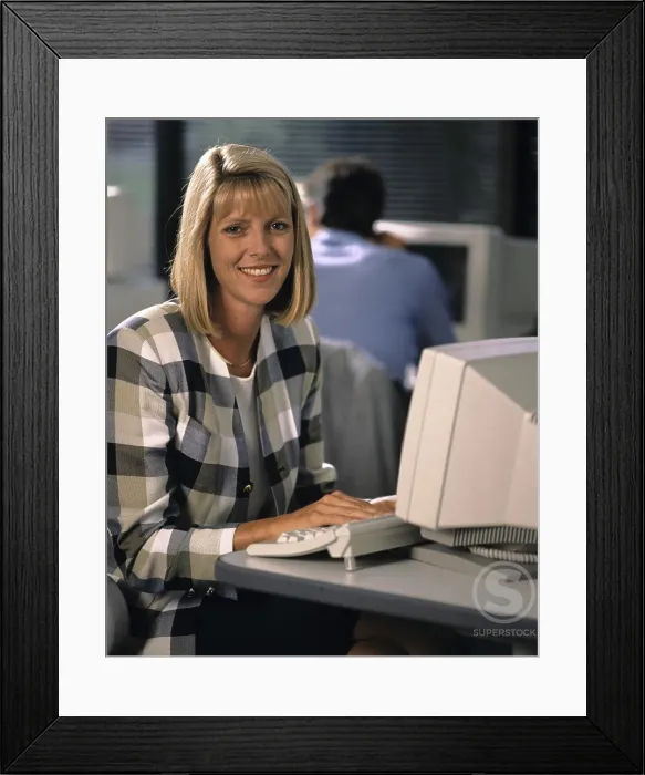 Framed Print : Businesswoman sitting in front of a computer and smiling Framed Print : Businesswoman sitting in front of a computer and smiling