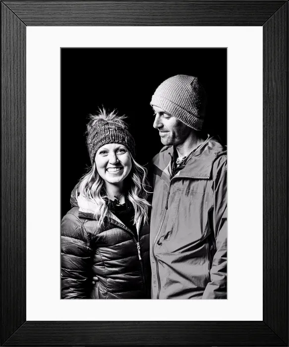 Framed Print : Smiling couple in warm clothing standing against black background Framed Print : Smiling couple in warm clothing standing against black background