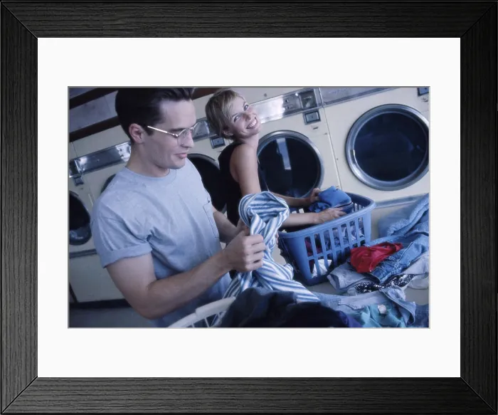 Framed Print : Young couple working in a laundromat