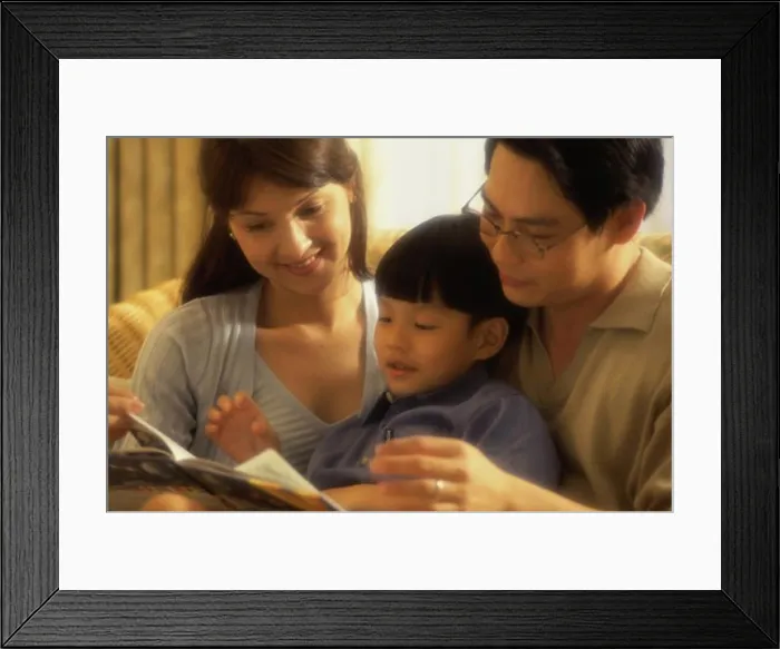 Framed Print : Parents with their son reading a book