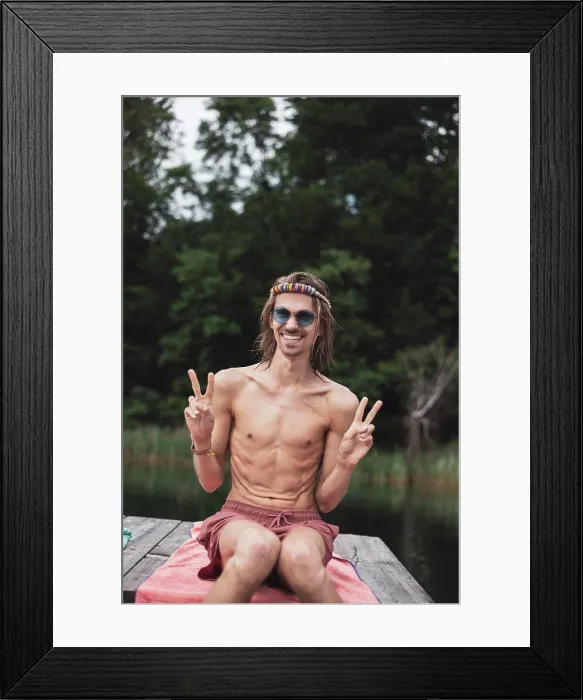 Framed Print : Smiling fit queer young man sitting by lake at festival in Poland Framed Print : Smiling fit queer young man sitting by lake at festival in Poland