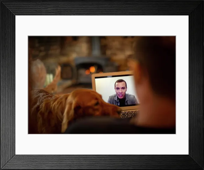 Framed Print : Man with dog video chatting with colleague on laptop screen Framed Print : Man with dog video chatting with colleague on laptop screen