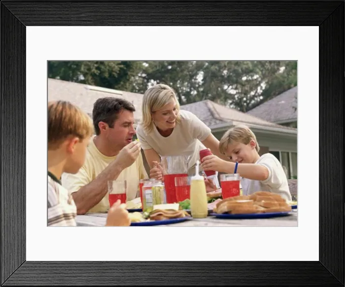 Framed Print : Mid adult woman serving food to her husband and two sons Framed Print : Mid adult woman serving food to her husband and two sons