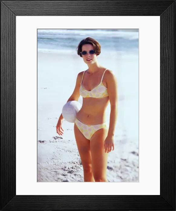 Framed Print : Young woman in a bikini holding a volleyball