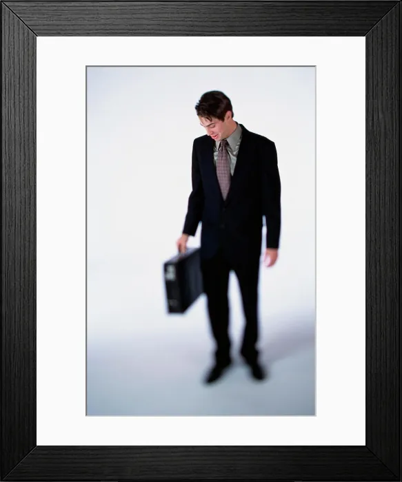 Framed Print : Businessman looking down while holding a briefcase Framed Print : Businessman looking down while holding a briefcase