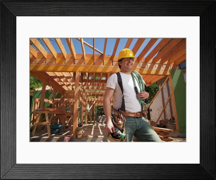 Framed Print : Portrait of a construction worker wearing a hard hat and a tool belt while standing on the construction site Framed Print : Portrait of a construction worker wearing a hard hat and a tool belt while standing on the construction site