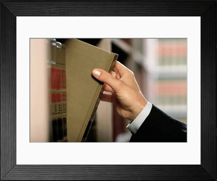 Framed Print : Close-up of a lawyer's hand removing a law book from shelf Framed Print : Close-up of a lawyer's hand removing a law book from shelf