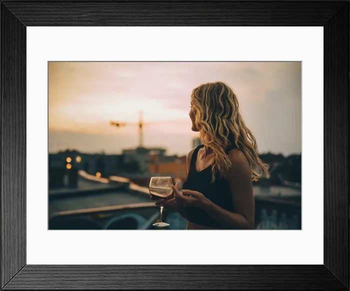 Framed Print : Thoughtful young woman having wine while looking away on terrace during rooftop party at sunset Framed Print : Thoughtful young woman having wine while looking away on terrace during rooftop party at sunset