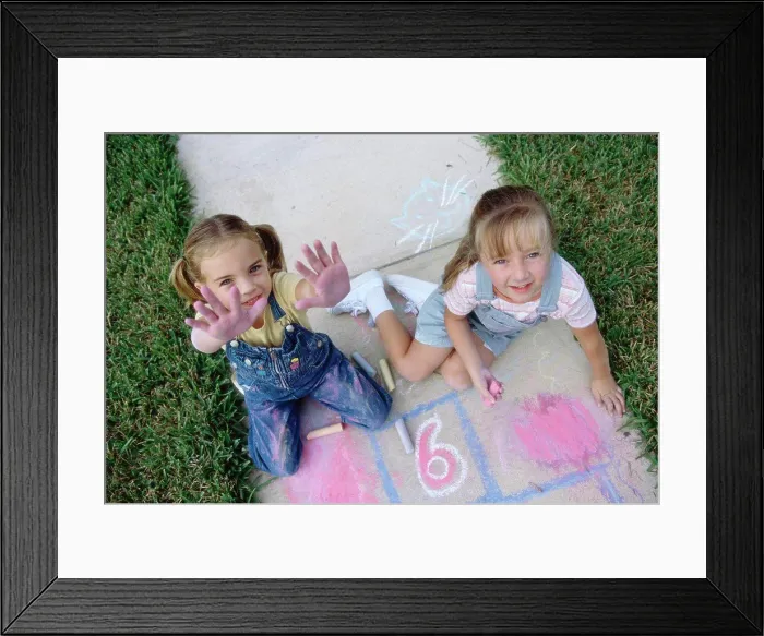 Framed Print : Portrait of two girls drawing on the ground with chalk Framed Print : Portrait of two girls drawing on the ground with chalk