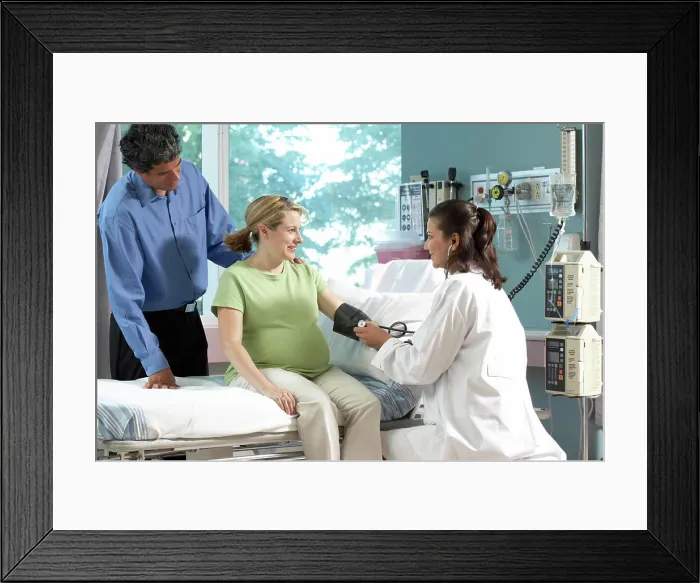 Framed Print : Side profile of a female doctor checking the blood pressure of a pregnant woman