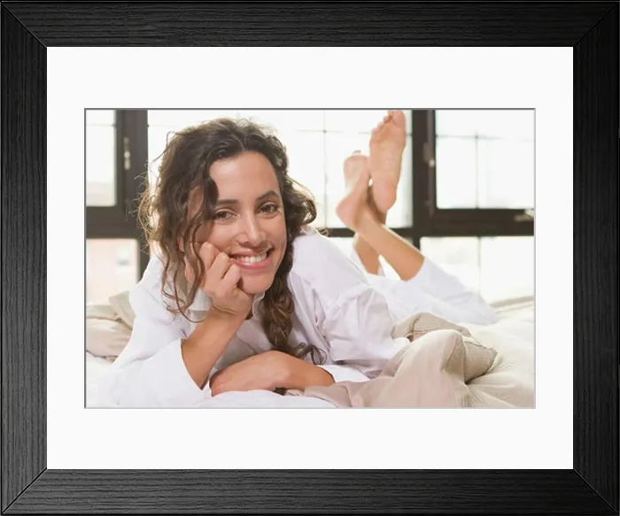 Framed Print : Portrait of a young woman lying on the bed and smiling Framed Print : Portrait of a young woman lying on the bed and smiling