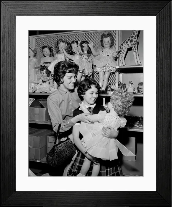 Framed Print : Mother and daughter observing doll in toy shop Framed Print : Mother and daughter observing doll in toy shop