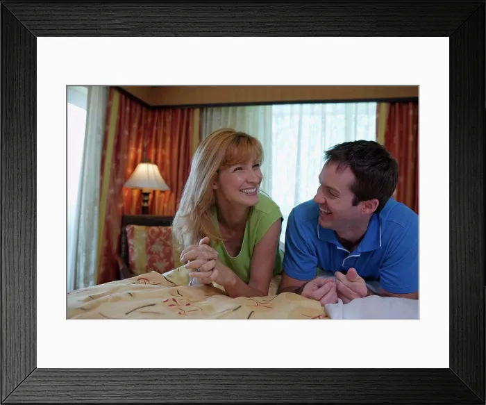Framed Print : Close-up of a young couple lying on the bed and smiling