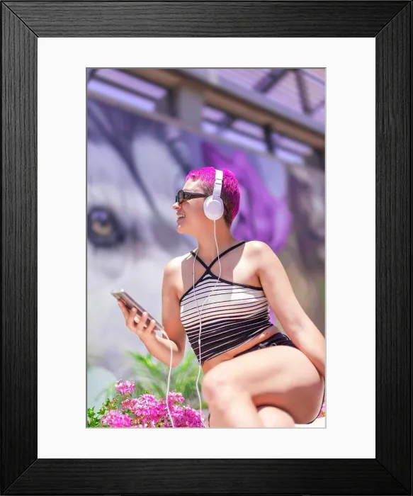 Framed Print : Woman with purple hair and headphones is listening music in her mobile