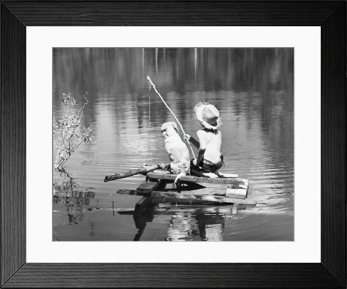 Framed Print : Rear view of a boy sitting with his dog and fishing in a lake Framed Print : Rear view of a boy sitting with his dog and fishing in a lake
