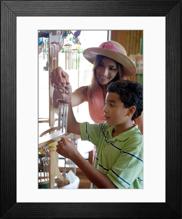 Framed Print : Young woman with her son holding a wind chime in store Framed Print : Young woman with her son holding a wind chime in store