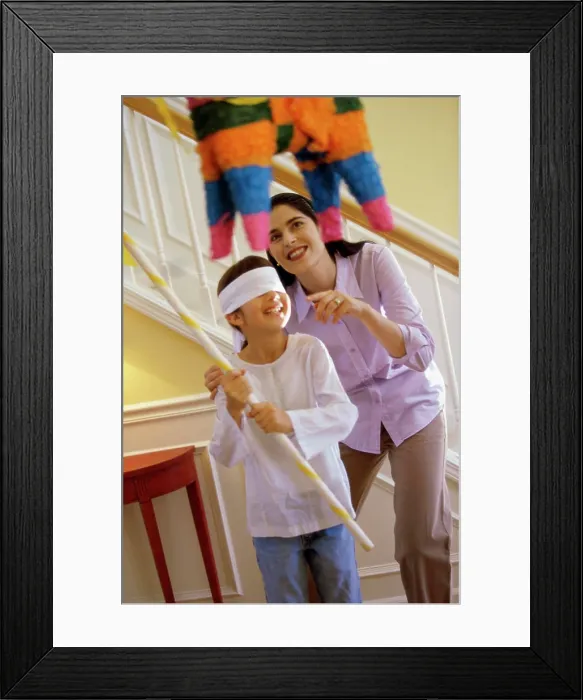 Framed Print : Mother helping her daughter hit a pinata Framed Print : Mother helping her daughter hit a pinata