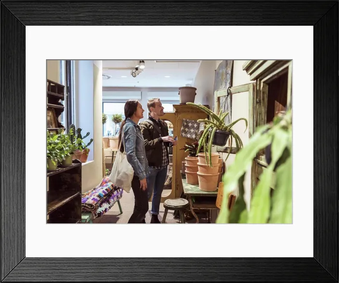 Framed Print : Smiling couple looking at wall decor while shopping in boutique Framed Print : Smiling couple looking at wall decor while shopping in boutique