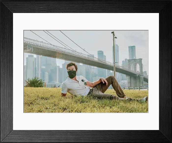 Framed Print : Young man sitting in park wearing face mask Framed Print : Young man sitting in park wearing face mask