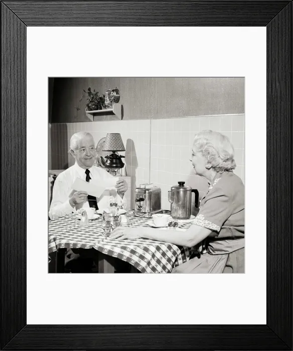 Framed Print : 1950s SENIOR COUPLE SITTING AT KITCHEN TABLE HAVING TOAST AND COFFEE MAN OPENING MORNING MAIL SMILING HOLDING CHECK