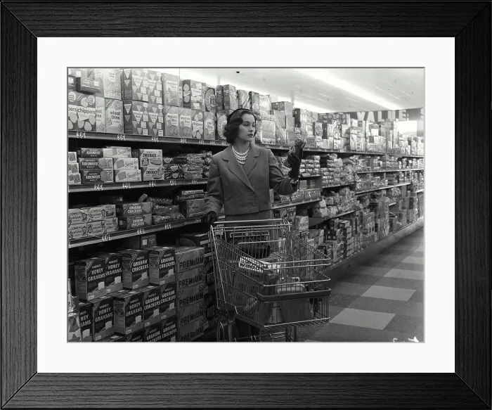 Framed Print : Young woman with a shopping cart in a grocery store