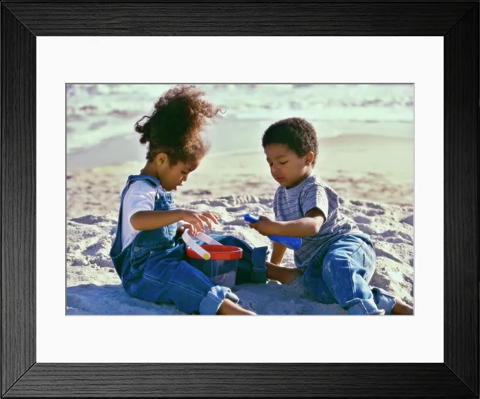Framed Print : Boy and a girl playing with a sand pail and a shovel on the beach