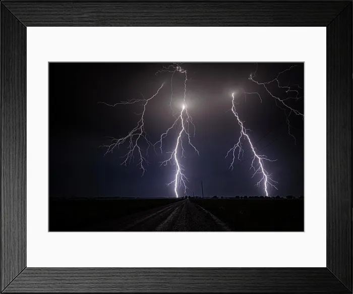 Framed Print : Storm with close range cloud to ground lightning flashing over old rural road in Kansas United States