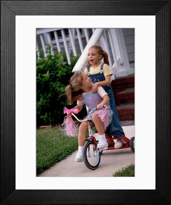 Framed Print : Two girls playing on a tricycle