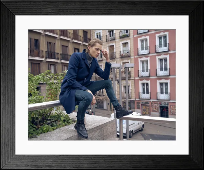 Framed Print : Low angle side view of serious elegant young male in stylish coat leaning on hand
