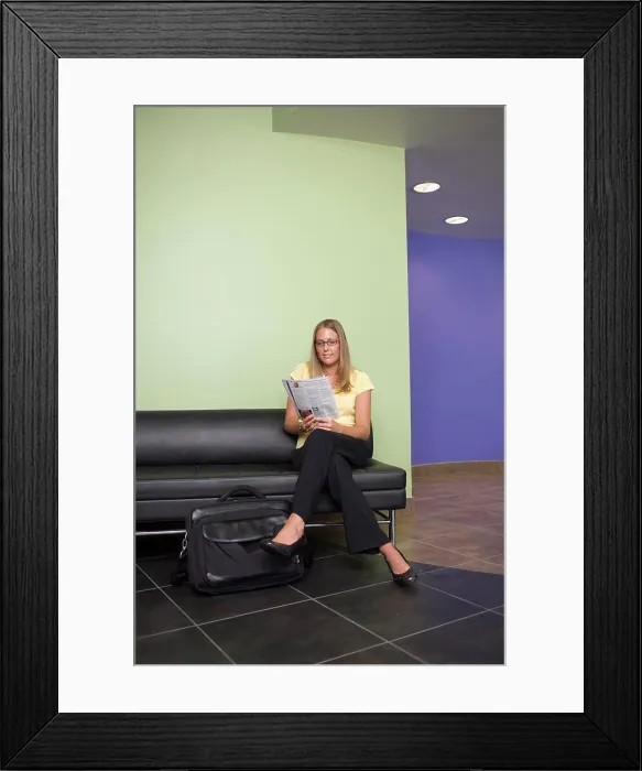 Framed Print : Businesswoman sitting on a couch reading a newspaper in an office Framed Print : Businesswoman sitting on a couch reading a newspaper in an office