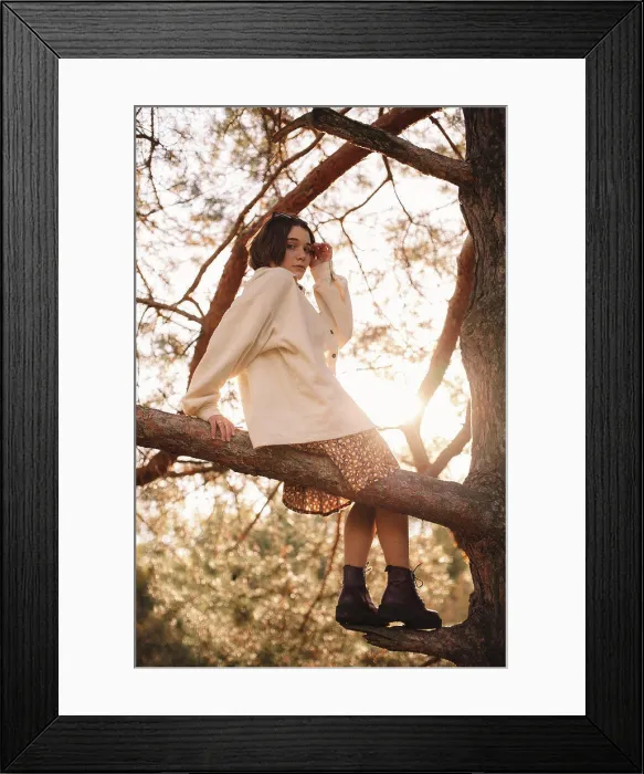 Framed Print : Young woman sitting on pine tree branch in forest
