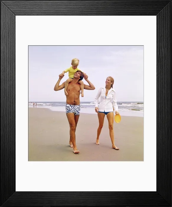 Framed Print : 1970s YOUNG FAMILY WALKING DOWN BEACH TODDLER RIDING ON FATHERS SHOULDERS