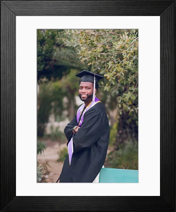Framed Print : Young man with arms crossed wearing a graduation gown / cap Framed Print : Young man with arms crossed wearing a graduation gown / cap