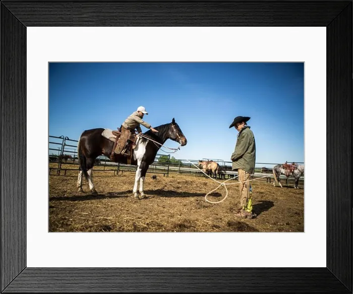 Framed Print : Young cowboy lassoing his father for practice