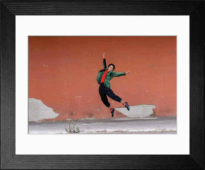 Framed Print : Italy, Tuscany, Pistoia, Smiling woman jumping against wall Framed Print : Italy, Tuscany, Pistoia, Smiling woman jumping against wall