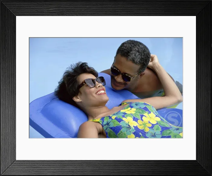 Framed Print : Mature woman lying on a pool raft with a mature man beside her Framed Print : Mature woman lying on a pool raft with a mature man beside her