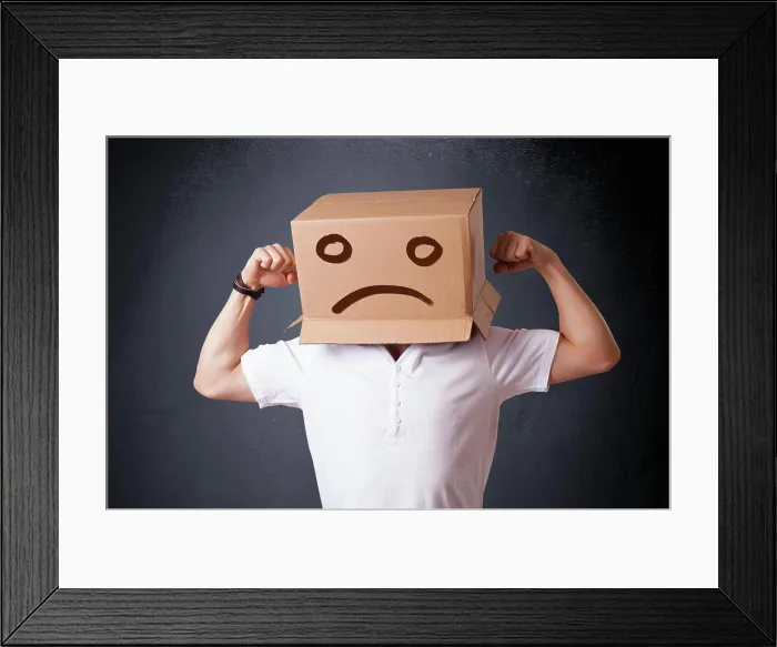 Framed Print : Junger Mann mit einem braunen Karton auf seinem Kopf mit traurigem Gesicht Young man standing with a brown cardboard