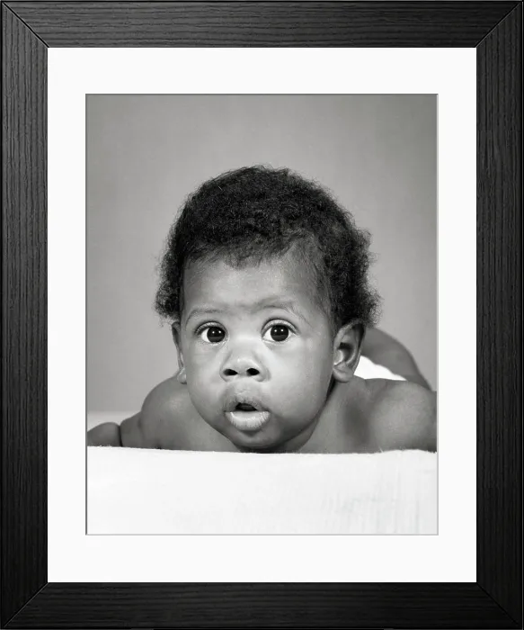 Framed Print : 1960s AFRICAN-AMERICAN BABY LAYING ON STOMACH FUNNY FACIAL EXPRESSION