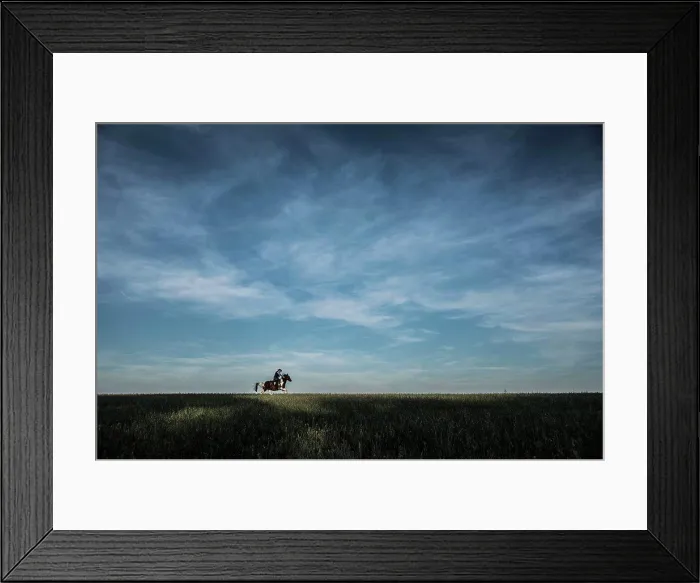 Framed Print : Cowboy riding horse in rural field under blue sky and clouds