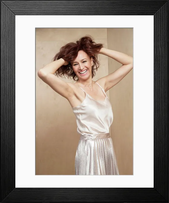 Framed Print : European looking middle-aged woman turns towards camera with her hands in hair, laughing