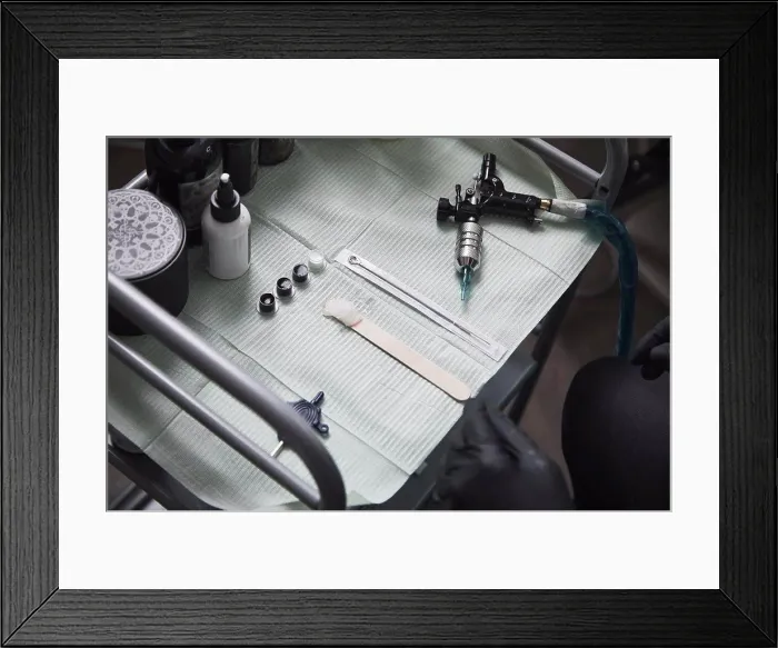 Framed Print : High angle view of tattoo artist sitting by tools on table Framed Print : High angle view of tattoo artist sitting by tools on table