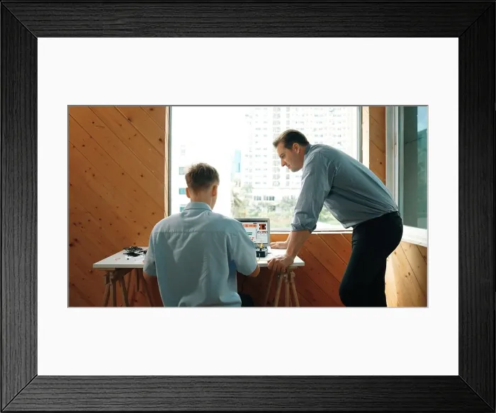 Framed Print : Skilled teacher looking at young highschool student fixing car model while laptop screen display coding engineering Framed Print : Skilled teacher looking at young highschool student fixing car model while laptop screen display coding engineering