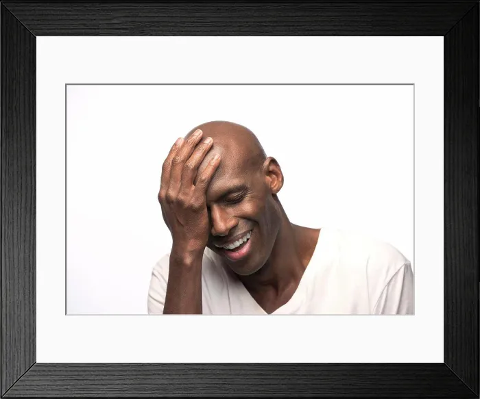 Framed Print : Portrait of young bald African American man with hand on his head looking down with eyes closed