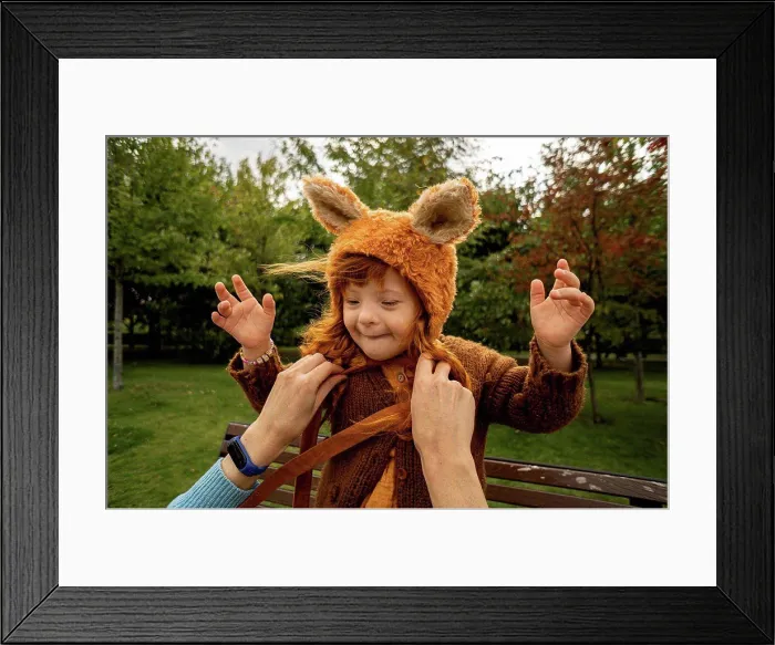 Framed Print : Mother tying bear costume hat of daughter at park Framed Print : Mother tying bear costume hat of daughter at park