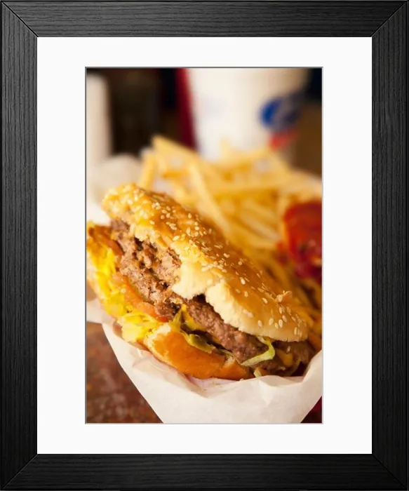 Framed Print : Close-up of a half eaten hamburger with fries in the background Framed Print : Close-up of a half eaten hamburger with fries in the background