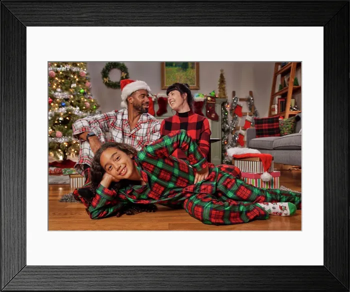 Framed Print : Portrait of a young African American girl laying on the floor looking into camera with her parents in the background