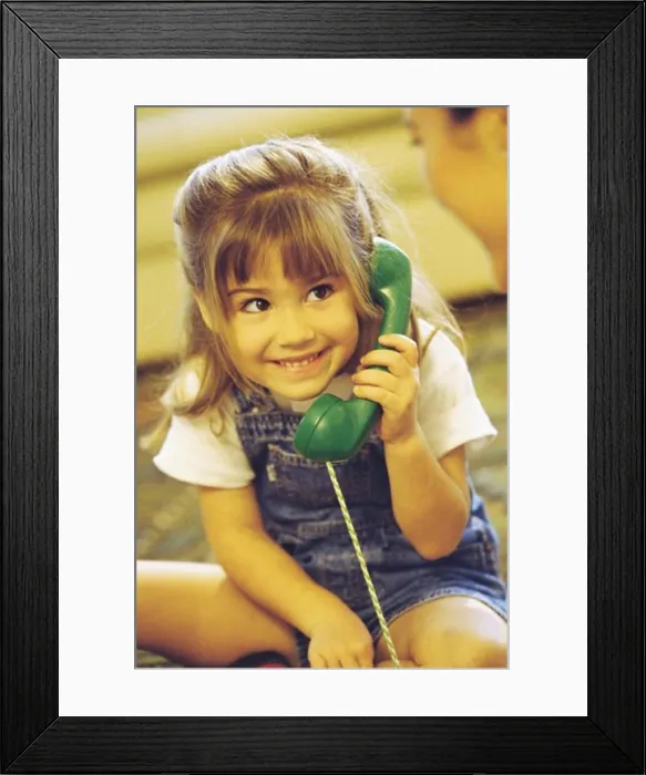 Framed Print : Girl holding a telephone receiver smiling Framed Print : Girl holding a telephone receiver smiling