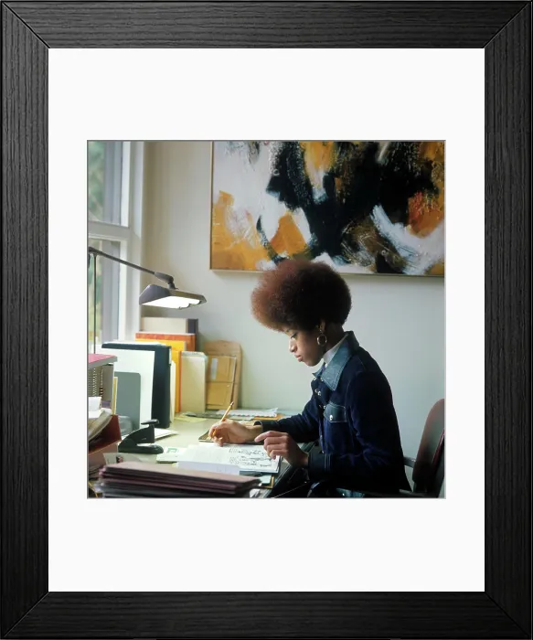 Framed Print : 1960S 1970S African American Woman Student Sitting At Desk Writing Papers By Window Light Afro Hair Style Denim Jacket Framed Print : 1960S 1970S African American Woman Student Sitting At Desk Writing Papers By Window Light Afro Hair Style Denim Jacket