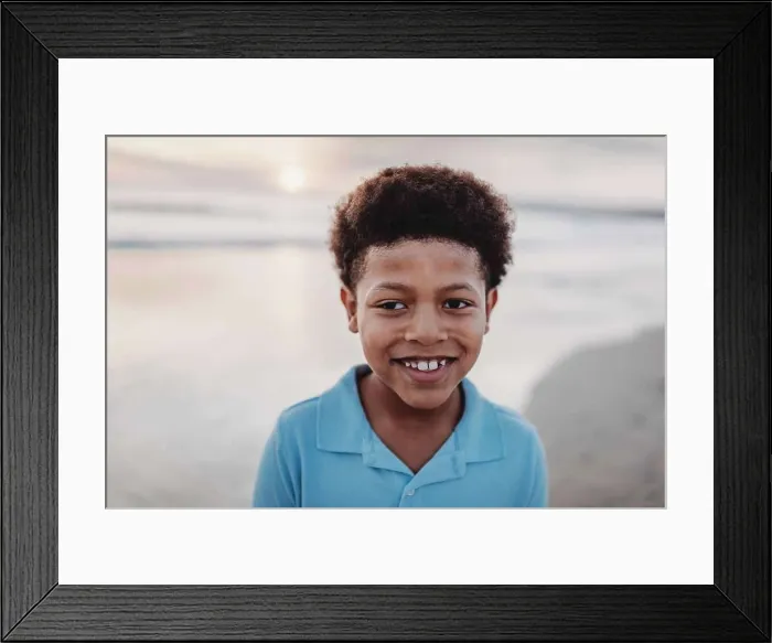 Framed Print : Portrait of young school-aged boy smiling at beach during sunset Framed Print : Portrait of young school-aged boy smiling at beach during sunset