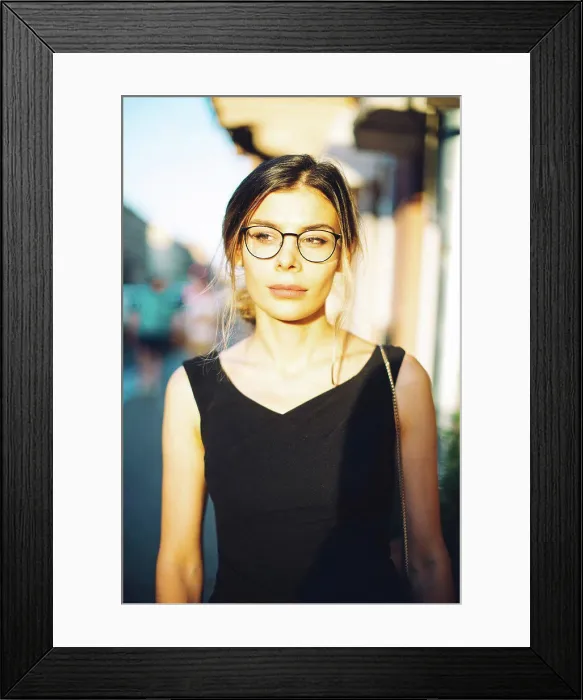 Framed Print : Young woman in black dress and glasses in the sunny city Framed Print : Young woman in black dress and glasses in the sunny city